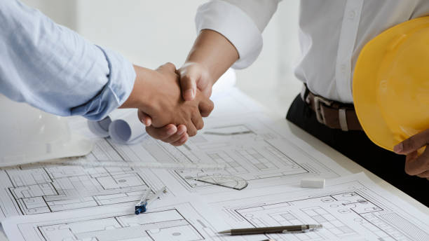Two engineer or architect meeting and greeting handshake after consultation and conference new project plan, makeing contract of both companies for partnership to success.